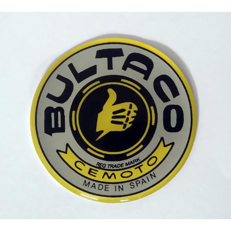 Anagrama deposito Bultaco color gris, borde amarillo.